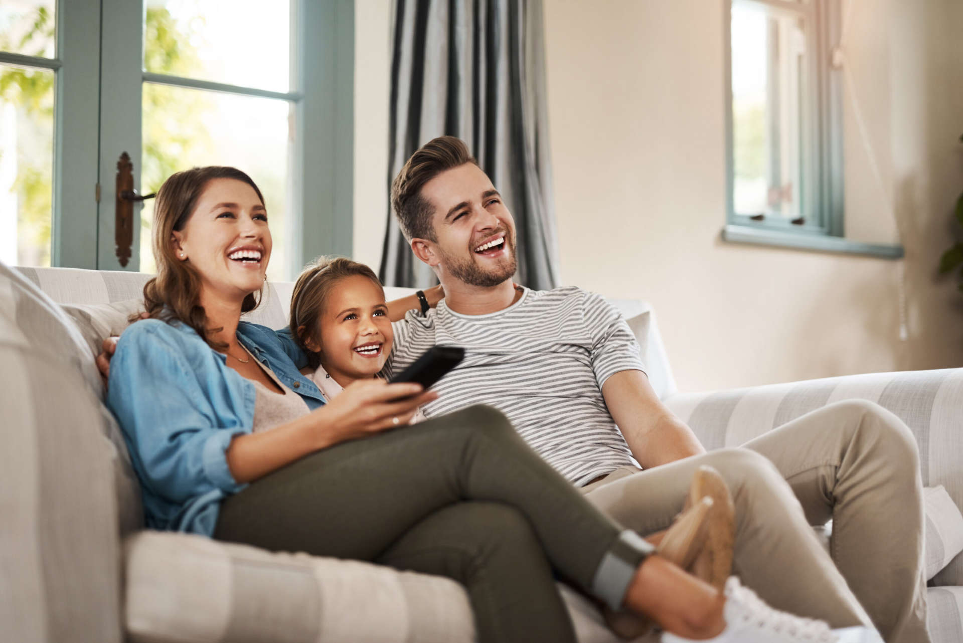 Shot of a happy young family relaxing on the sofa and watching tv together at home